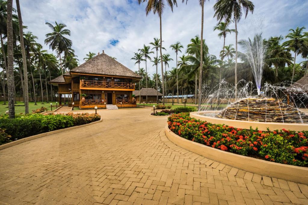 a fountain in front of a building with palm trees at Maaha Beach Resort in Anochi