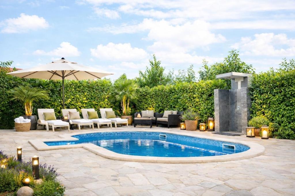 a swimming pool in a yard with chairs and an umbrella at Studio apartment with pool in Pula