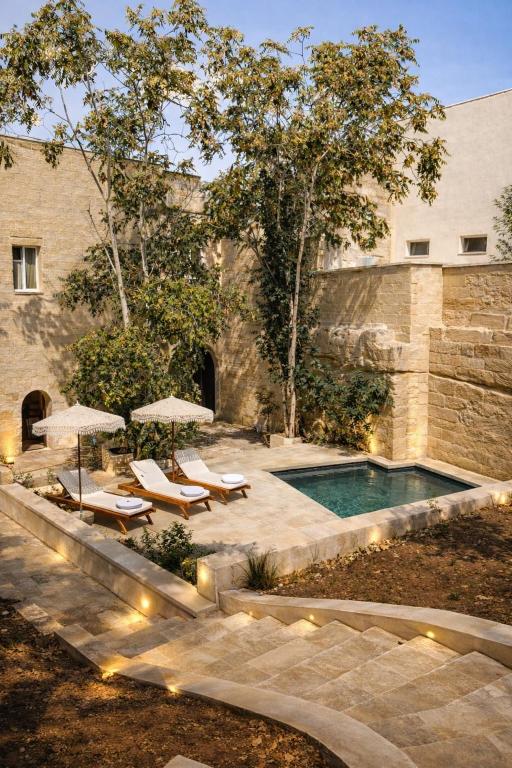 a swimming pool with chairs and umbrellas and a building at CAVA Urban Relais & Pool in Lecce