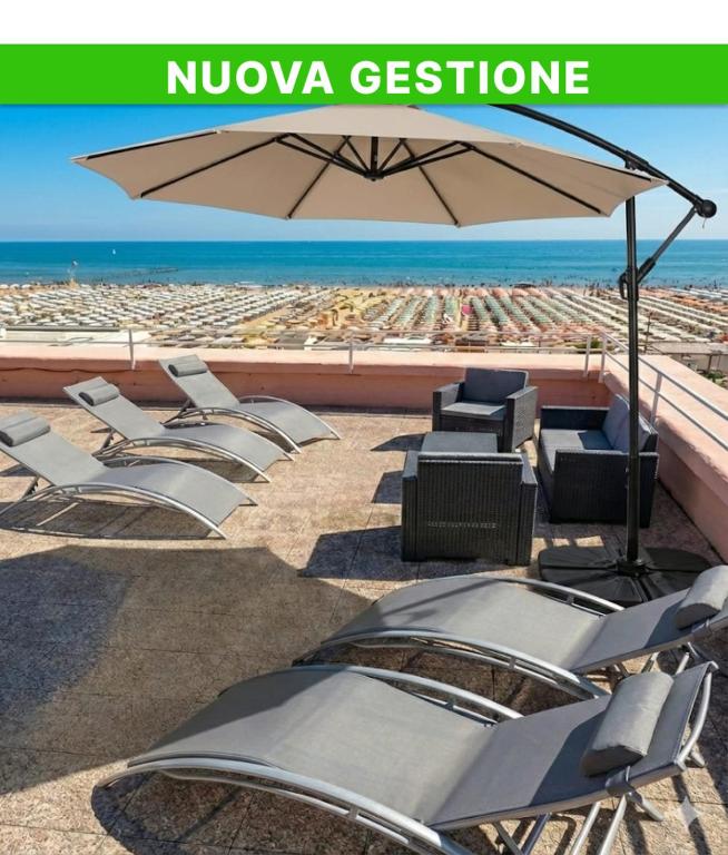 a group of chairs and an umbrella on a beach at Hotel Bel Air Frontemare in Rimini