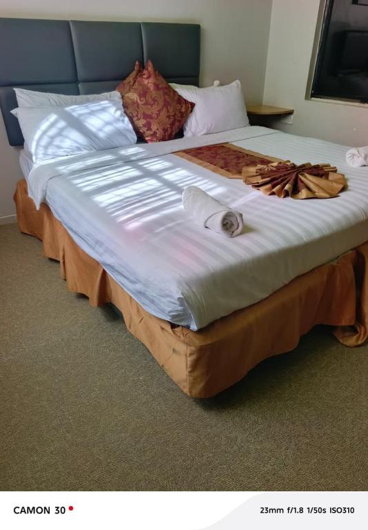 a large bed with white sheets and pillows on it at Maple inn & Resort in Nairobi