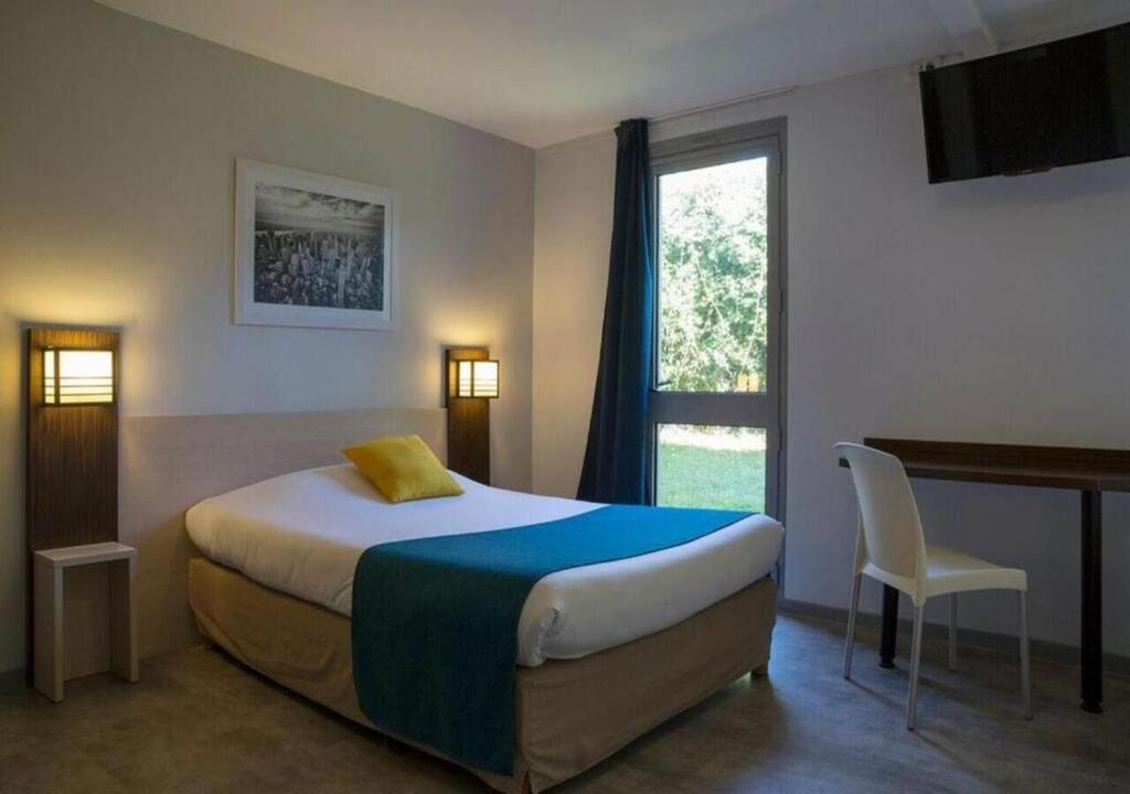 a bedroom with a bed and a desk and a window at The Originals City, Hotel Novella Confort, Nantes Est in Carquefou