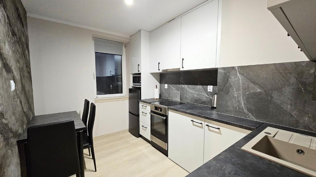 a kitchen with white cabinets and a table and a sink at Piękna 20 Residence in Łomża