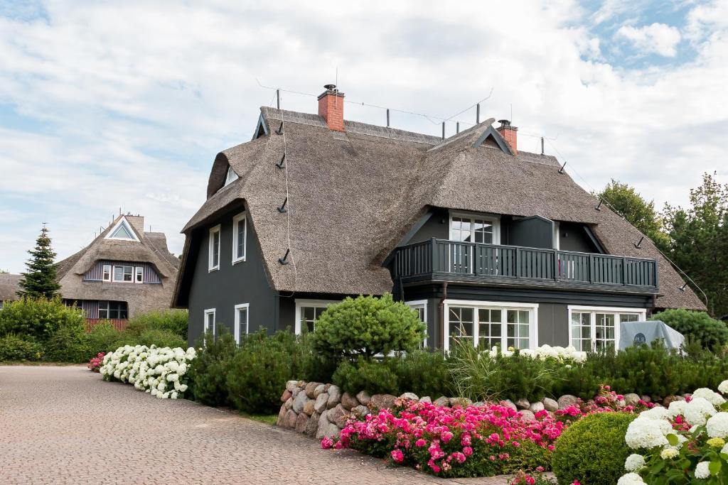 a black house with a gray roof and flowers at Pur A4 in Wustrow