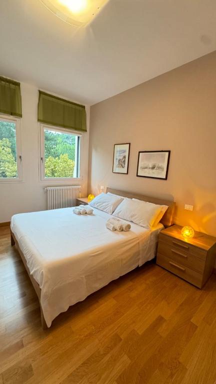 a bedroom with a large white bed and two windows at Dimora delle Terme in Porretta Terme