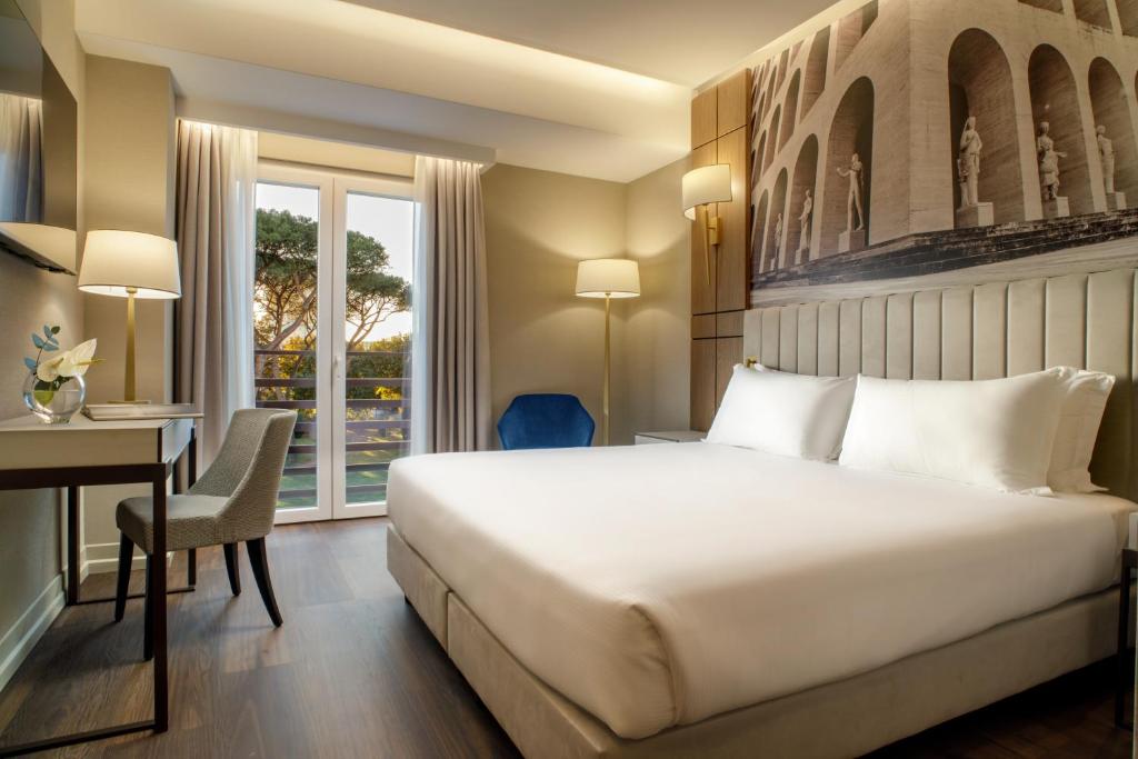 a hotel room with a bed and a desk and a window at Hotel Shangri-La Roma by OMNIA hotels in Rome