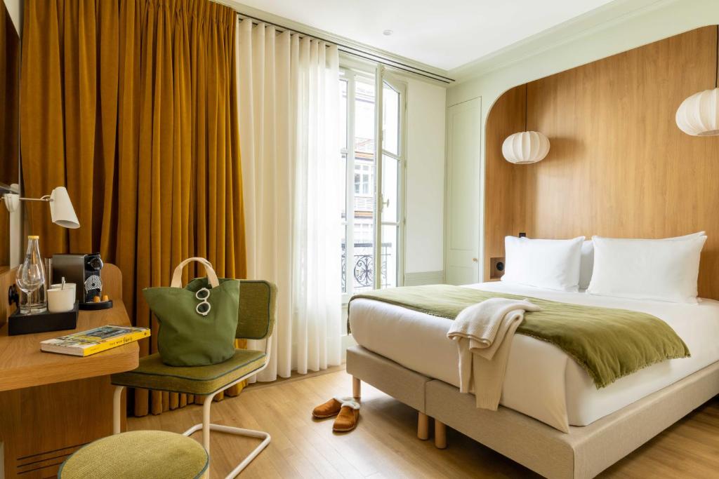 a bedroom with a bed and a desk and a window at Hôtel Casimir in Paris