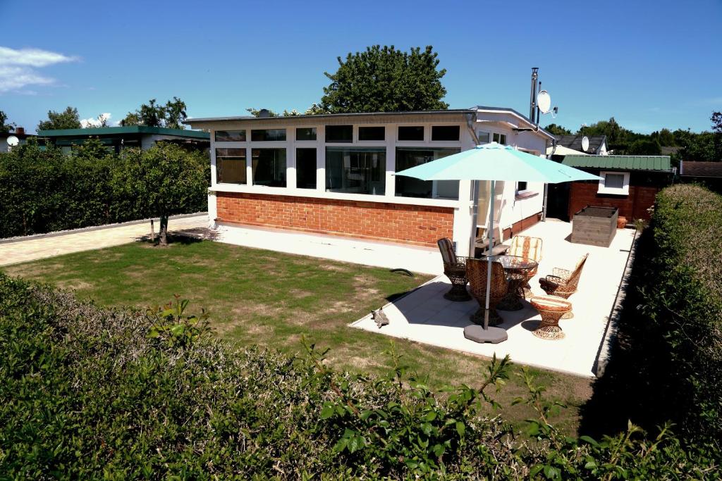 a house with a table and an umbrella and chairs at Ferienbungalow Strandluft in Loissin