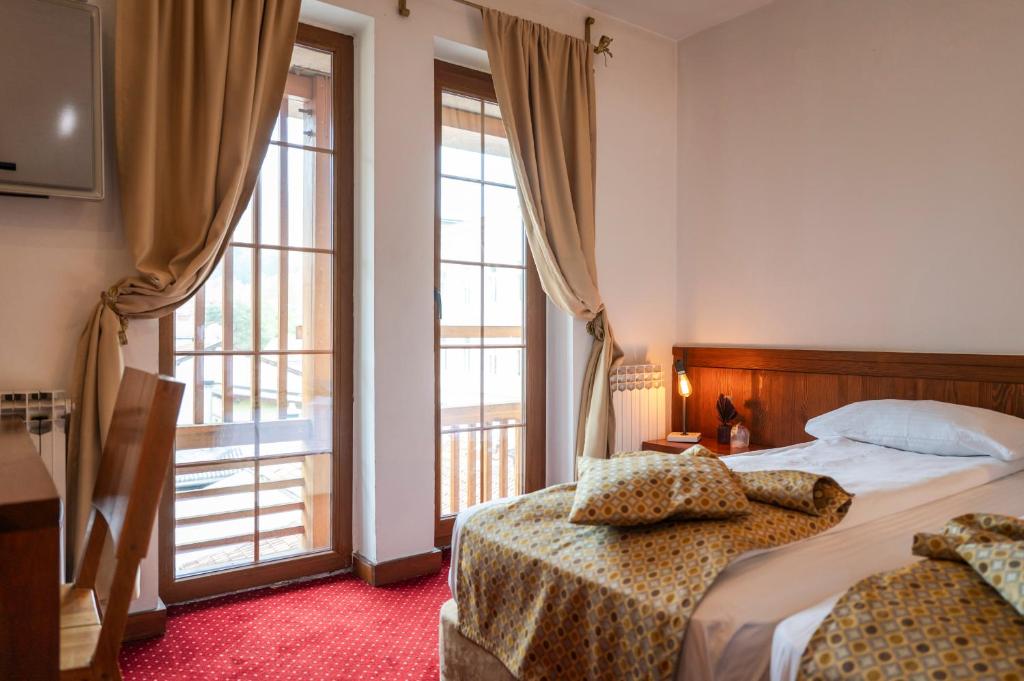 a bedroom with two beds and a large window at Garni Konak Hotel By Blanket Collection in Sarajevo