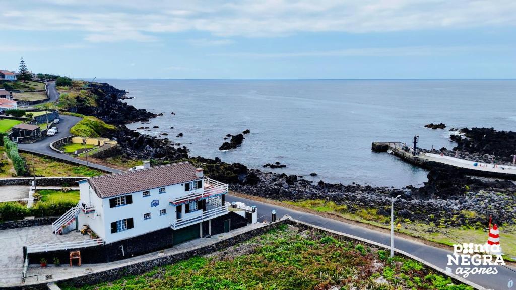 a white house on the side of a road next to the ocean at Casa da Maresia by PontaNegraAzores in Biscoitos