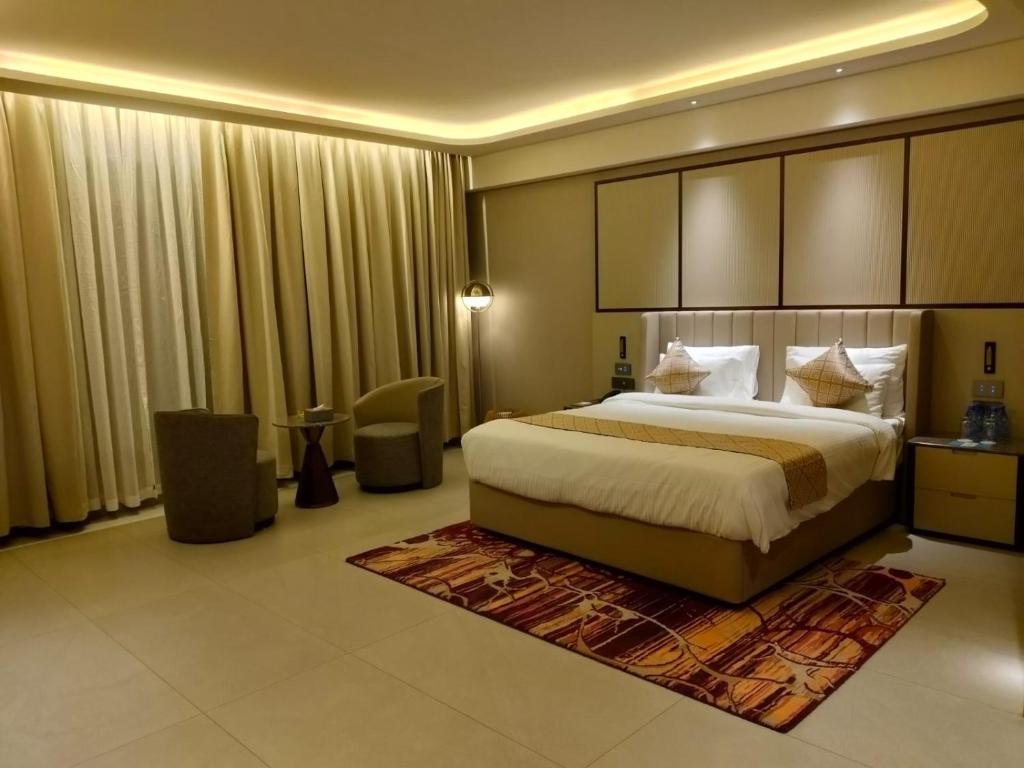 a bedroom with a large bed in a room with curtains at La Belle - The Business Hotel in Lubumbashi