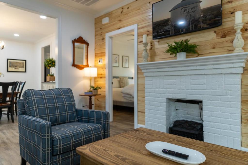 a living room with a fireplace and a blue chair at Mimosa Cottage - Thomasville Charm in Thomasville