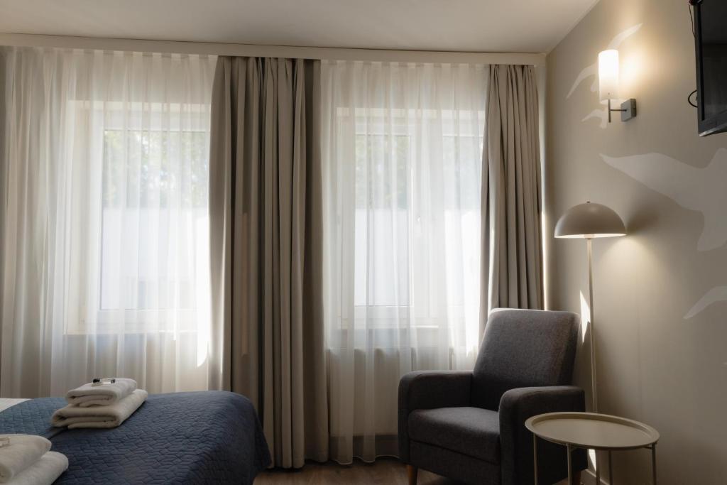 a hotel room with a bed and a chair and a window at Villa Flaming in Sopot