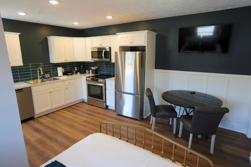 a kitchen with a table and a refrigerator at Modern Queen Studio At The Victorian - Unit B in Muskegon