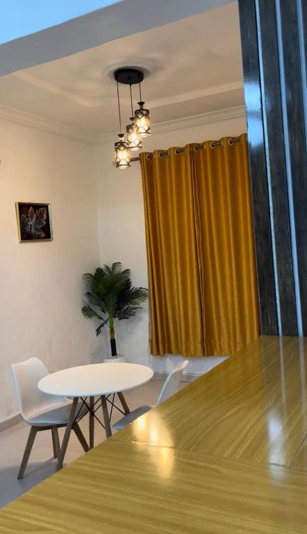 a dining room with a table and chairs and a yellow curtain at AG Sigma Apartments in Port Harcourt