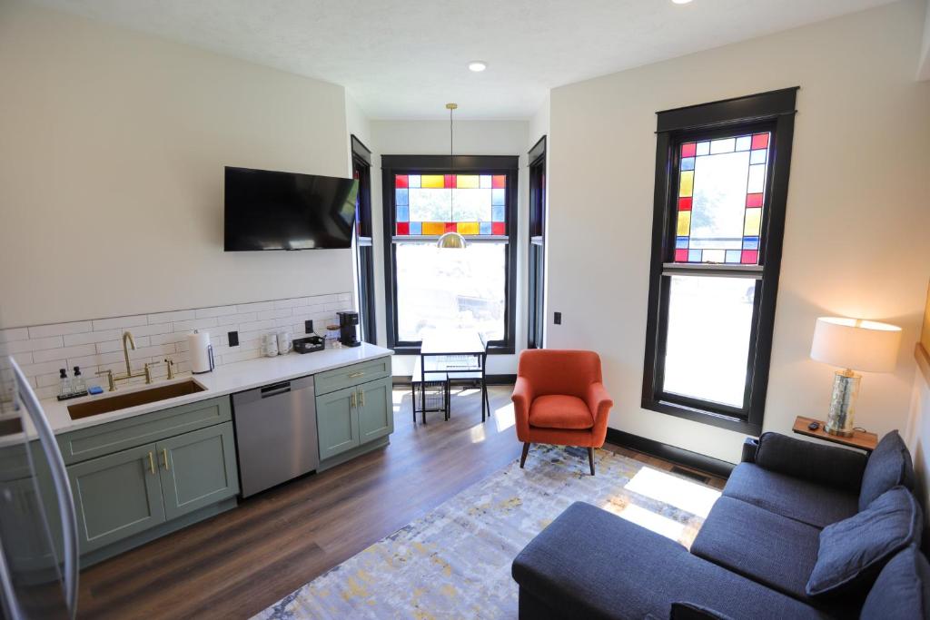 a living room with a couch and a kitchen with stained glass windows at Chic Queen Apartment At The Victorian Unit A in Muskegon