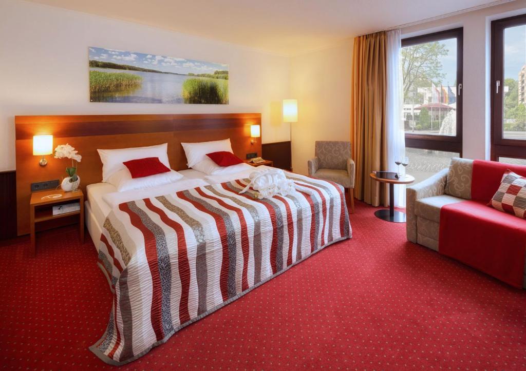 a hotel room with a large bed and a red carpet at A&S City Hotel am Rosenpark in Aachen
