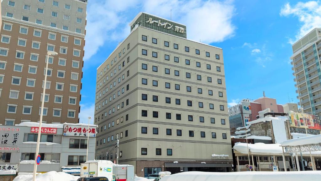 a tall building with a sign on top of it at Hotel Route-Inn Aomori Ekimae in Aomori