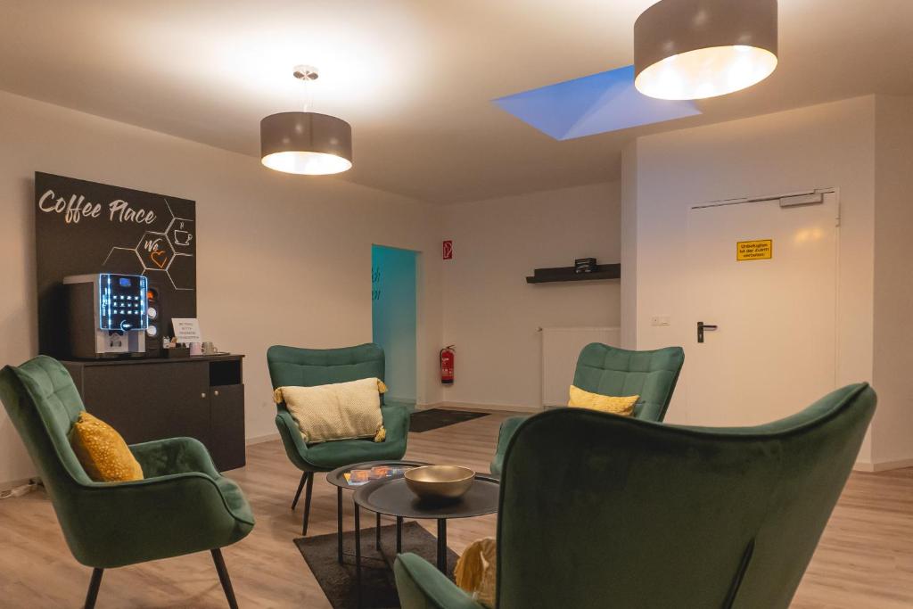 a waiting room with green chairs and a table at Infinity Stay Apartmenthaus am Park in Wilhelmshaven