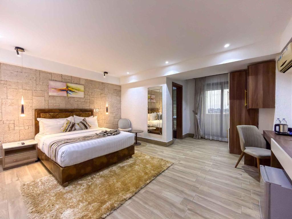a hotel room with a large bed and a desk at Blue Orange Hotel and Towers in Shomolu