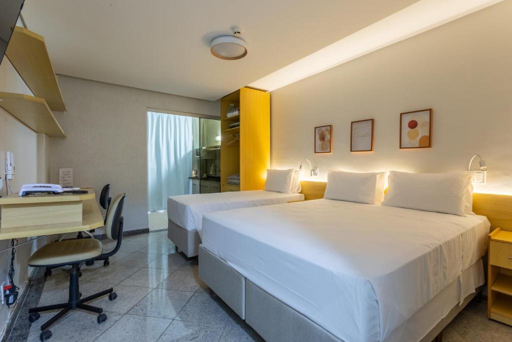 a hotel room with two beds and a desk at Flat - Excelente localização - Hotel Garvey in Brasília
