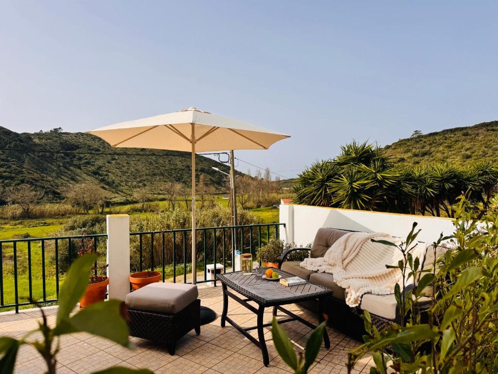 a patio with a couch and an umbrella and a table at Casa Nabia - Coastal Sanctuary in Ericeira