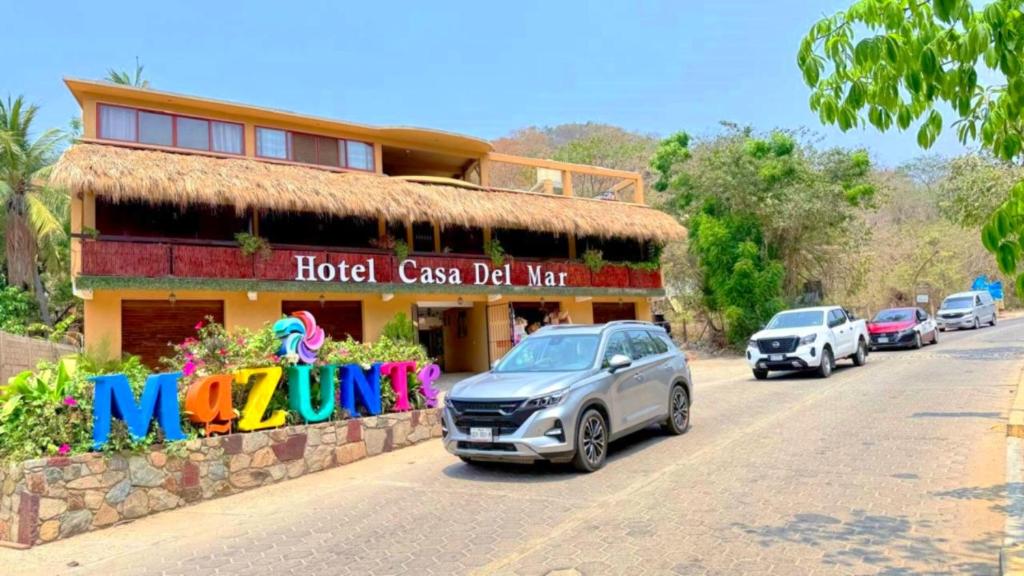 a hotel with cars parked in front of a building at Hotel Casa del Mar Mazunte in Santa María Tonameca