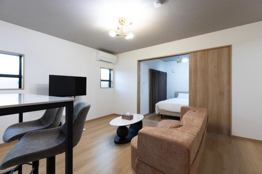 a hotel room with a bed and a desk and chairs at Bio Top Apartment Stay in Fukuoka