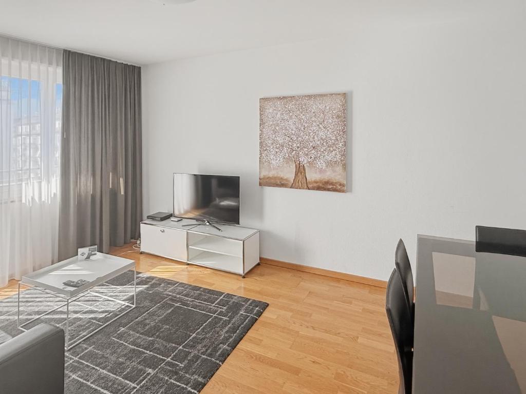 a living room with a television and a table at Cozy 1BR near lake with balcony - Mill 422 in Zurich