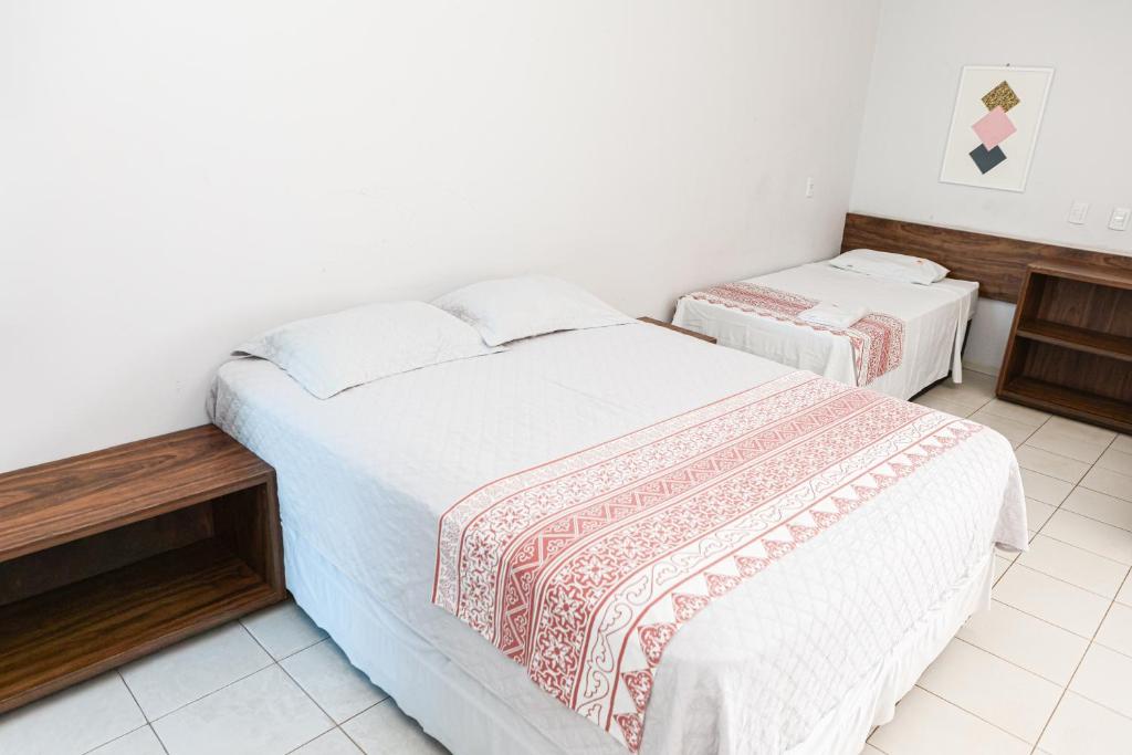 two beds in a room with white walls at San Felipe Hotel in Colinas do Tocantins
