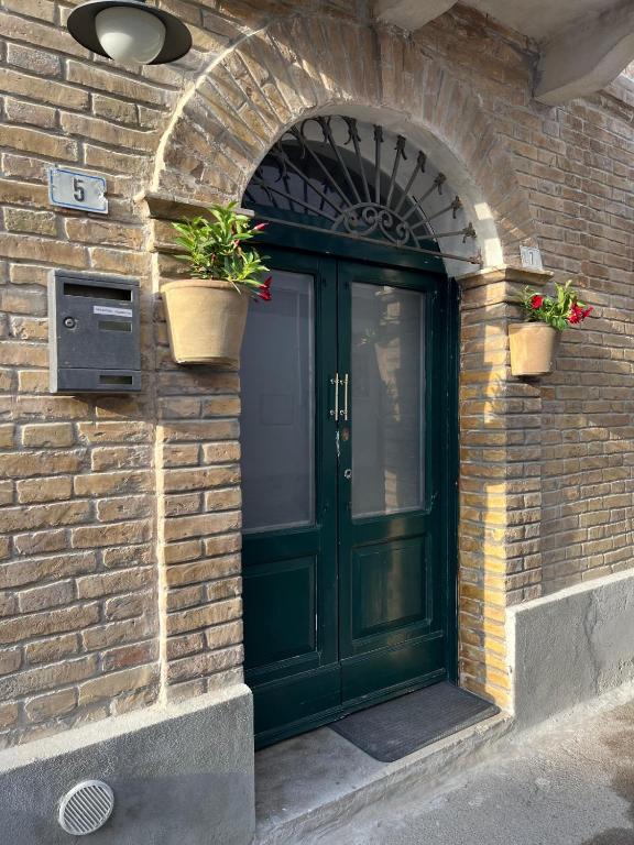a green door on a brick building with two potted plants at Casa CAMILLA in Vasto