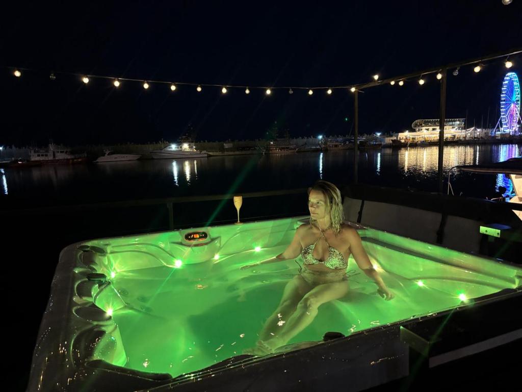 a woman sitting in a bathtub in the water at night at SeaEsta Floating Houses in Constanţa