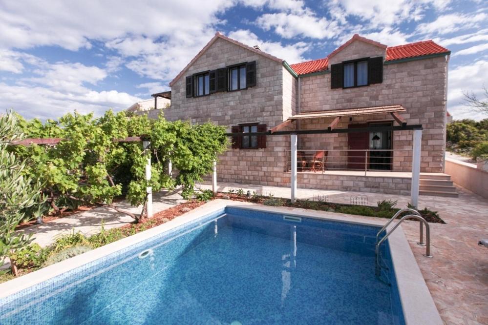 a house with a swimming pool in front of a house at Vila Venecija in Povlja
