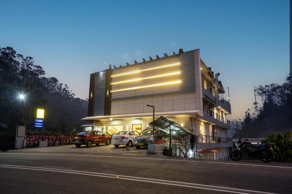 a building with cars parked in a parking lot at Las Palmas in Munnar