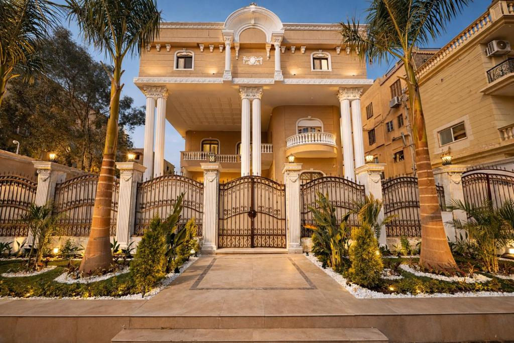 a large building with a gate and palm trees at Cairo Stays Hotel in Cairo