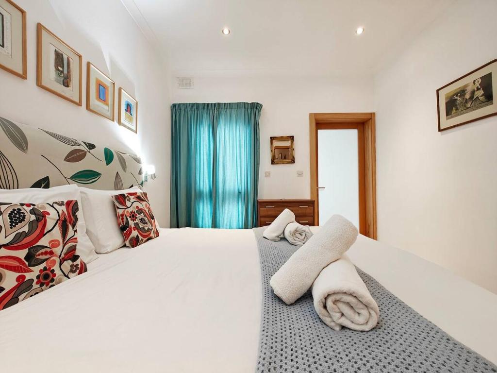 a bedroom with a white bed with towels on it at Good Times in Sliema