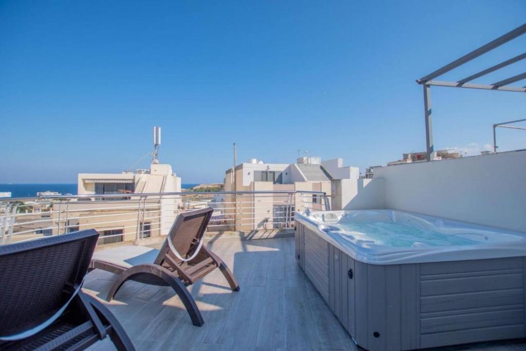 a hot tub and chairs on a balcony at The Terrace in Xgħajra