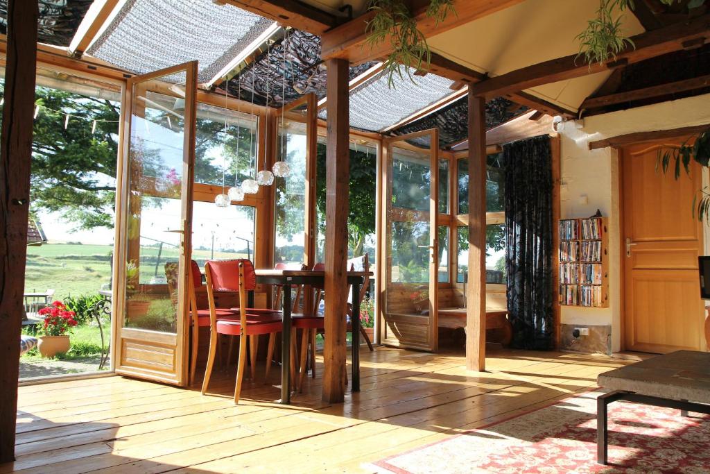 a conservatory with a table and chairs and glass doors at The charming, bright stable in Neuilly-le-Dien