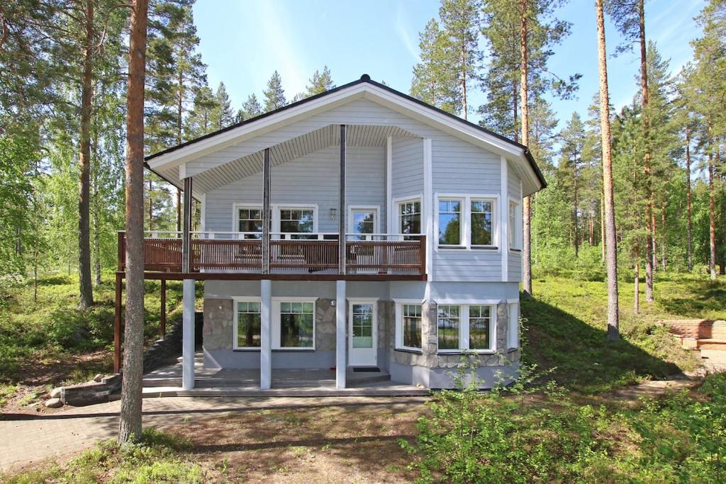a house with a wrap around deck in the woods at Pielusrinne in Hattusaari