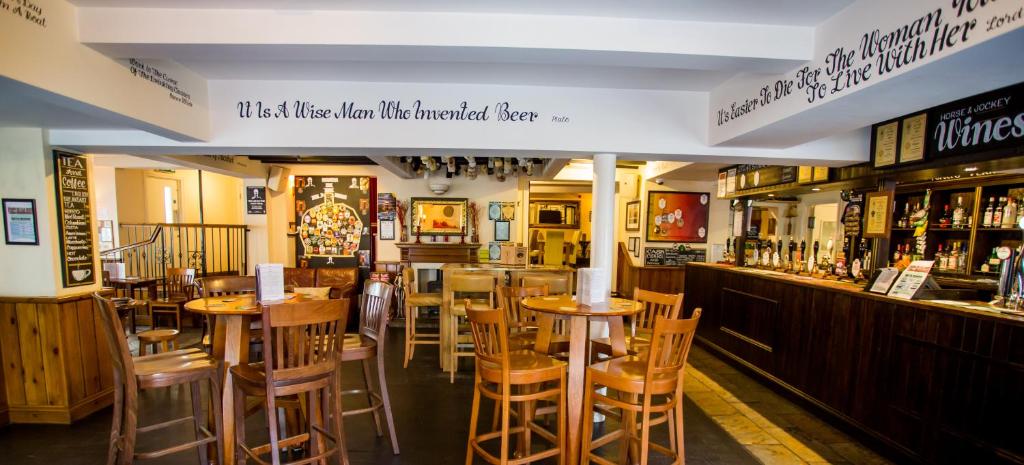 um restaurante com mesas e cadeiras de madeira e um bar em The Horse and Jockey em Stapleford