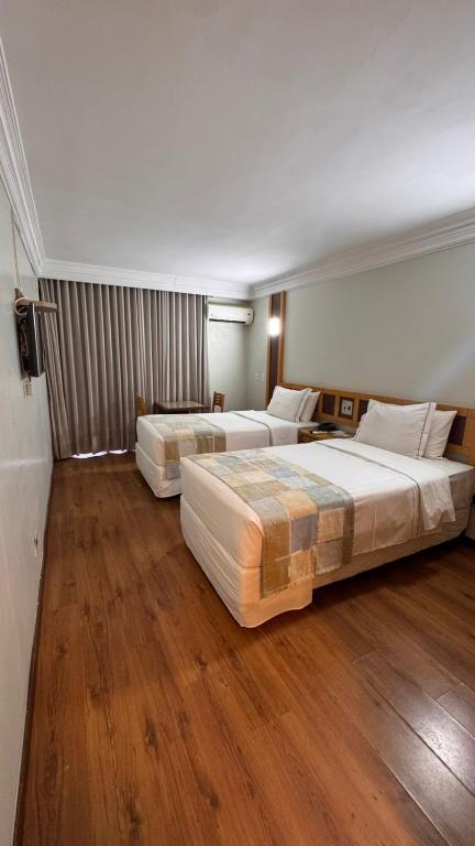 two beds in a hotel room with wooden floors at Monumental Bittar Hotel in Brasília