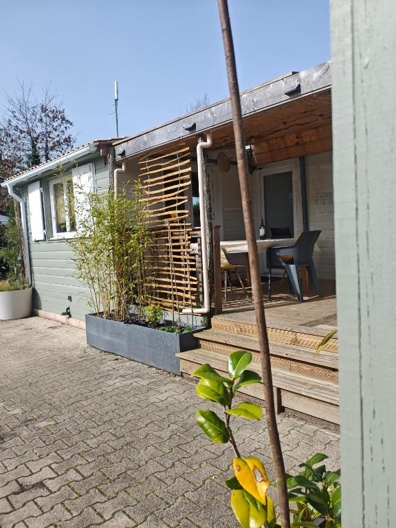 a house with a wooden deck with a table at Maison 47m2 climatisé, piscine,linge fourni in Gujan-Mestras