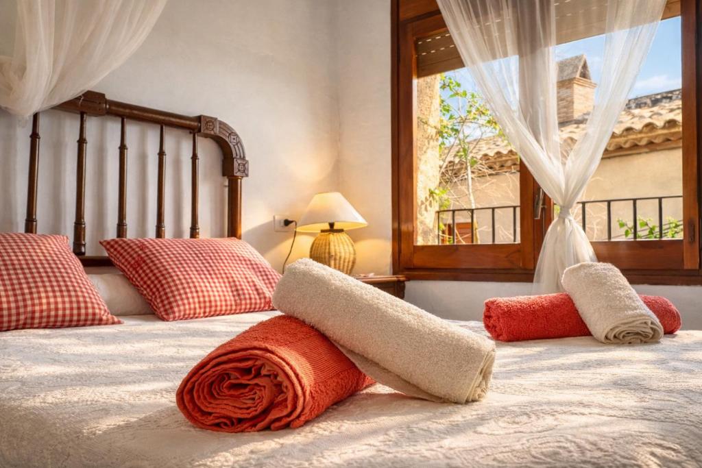 a bed with red and white pillows and a window at Casa rural amb cova - Cal Gravat in Montsonis
