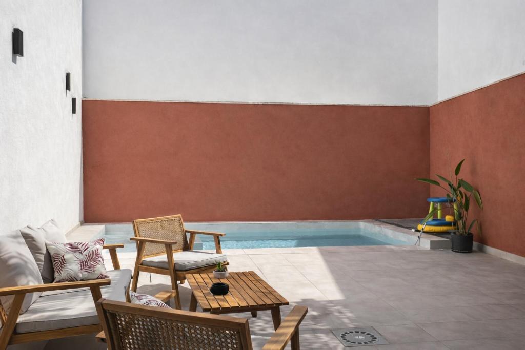 a swimming pool in a room with chairs and a couch at Apartamento Maya Merida in Mérida