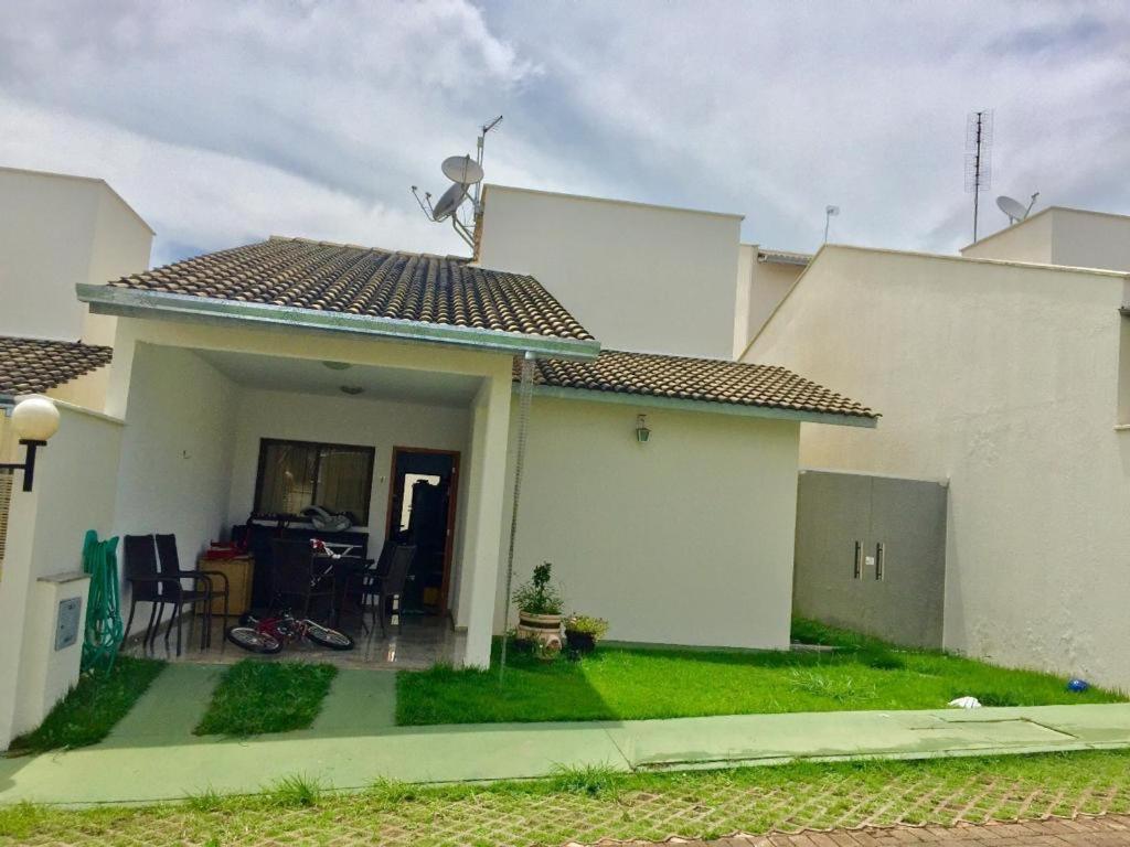 a white house with a porch and a yard at Casa mobiliada BR 153 in Aparecida de Goiânia
