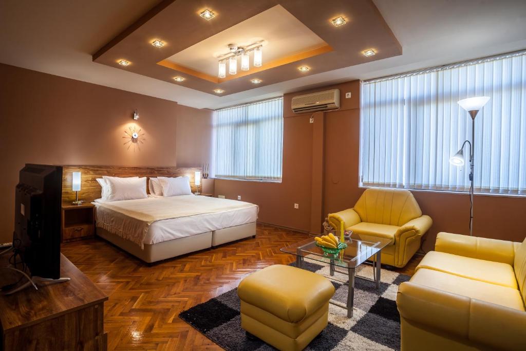 a bedroom with a bed and a tv and a couch at Panorama Top Floor Rooms in Hotel Tundzha in Yambol
