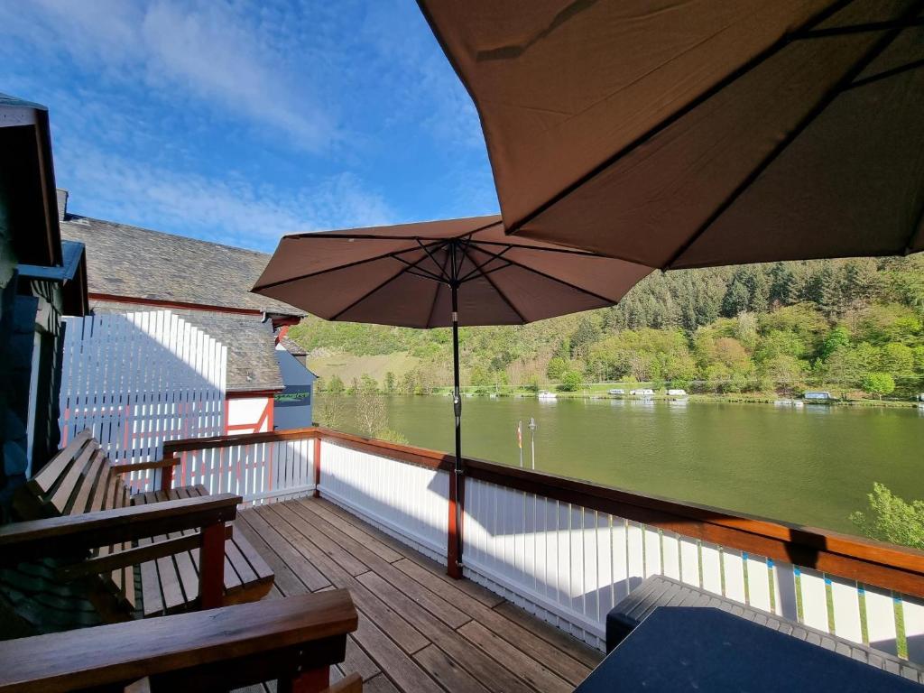 a balcony with an umbrella and a view of a river at Traum-Fewo Mosel-Panoramablick in Traben-Trarbach