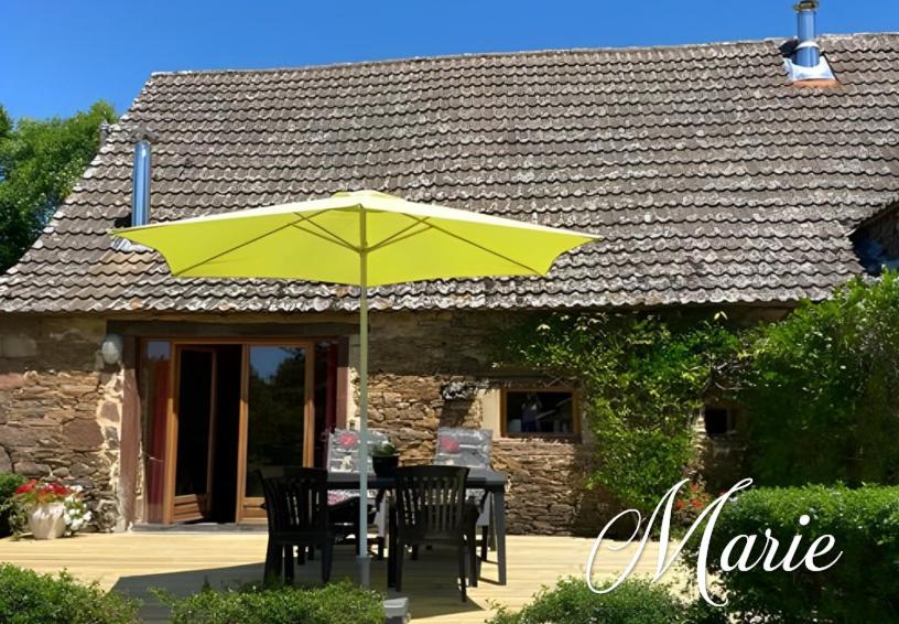 a table with a yellow umbrella in front of a house at Gîte Marie, Beynat, Corrèze in Beynat