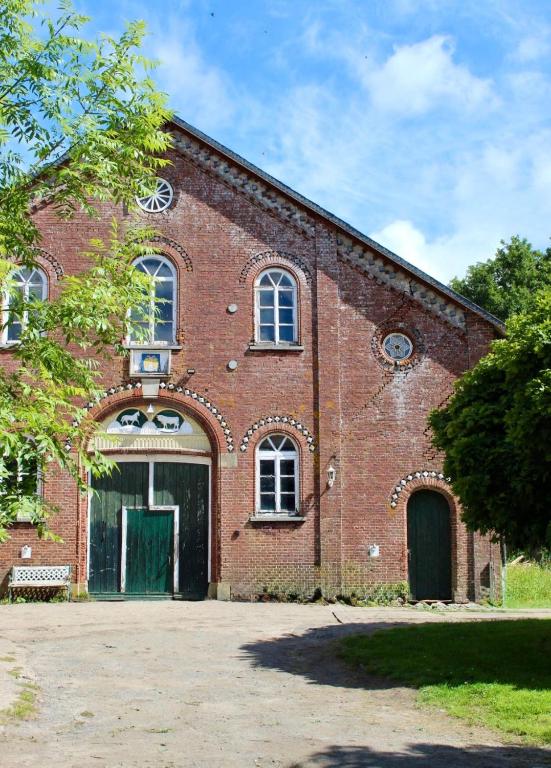 a large brick building with a green door on it at Gut Osterhausen in Butjadingen