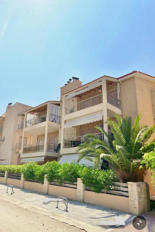 a large building with a palm tree in front of it at Oikos Apartment in Hanioti